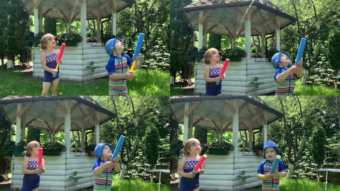 可爱的快乐的孩子，学龄前的小女孩和男孩的孩子玩有乐趣的水泵枪在外面。阳光明媚，公园里的一天。儿童后院