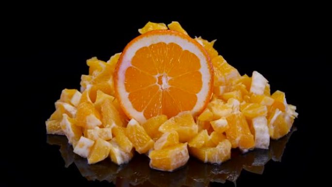 黑色背景上的橙色和橙色切片。4K新鲜，完美，多汁的有机橙子。