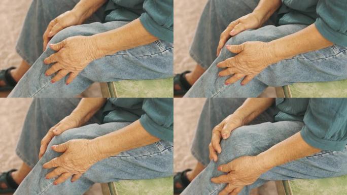 近距离4k坐着的老年人膝盖，手触摸或抓着，因为感觉疼痛和受伤，显示老年人由于肌肉无力和关节疼痛而导致