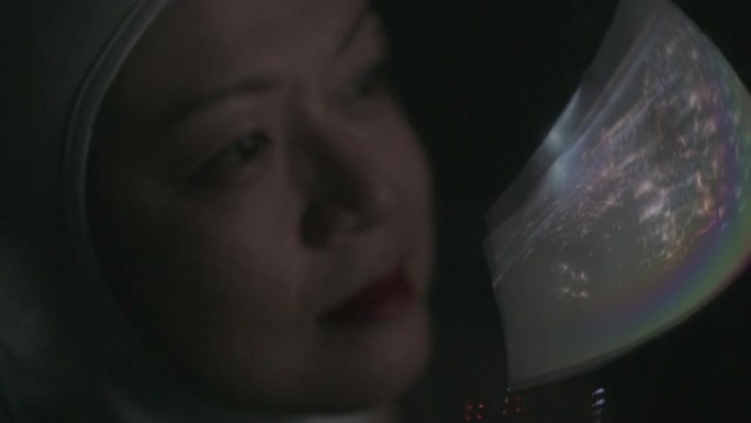 亚洲中国中年女宇航员从太空飞船通过窗户看着地球
