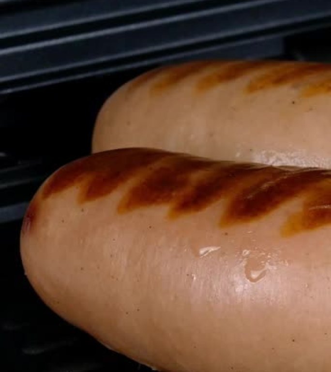 厚而油腻的香肠在电烤架上油炸。垂直视频。特写。