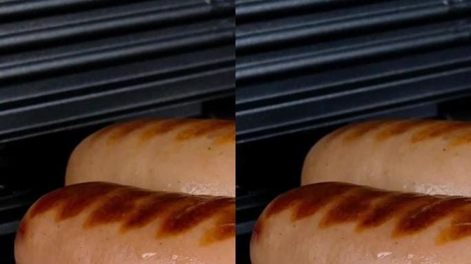 厚而油腻的香肠在电烤架上油炸。垂直视频。特写。