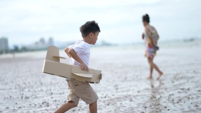 亚洲孩子在海滩玩纸板飞机