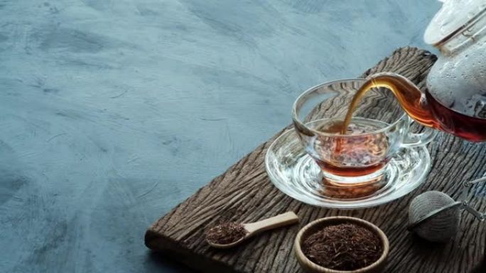 过程冲泡茶，将热茶水从茶壶倒入杯子中，放在带有深色厨房餐桌背景的旧木板上，静物放松时光阴暗的心情风格