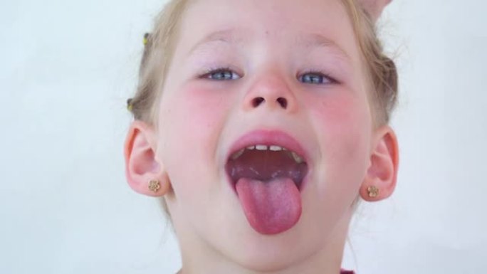 一个小女孩露出舌头喉咙。张大嘴，舌头突出的肖像。视野清晰，伸出长长的舌头。牙医的软腭和嘴巴。嘴巴张开