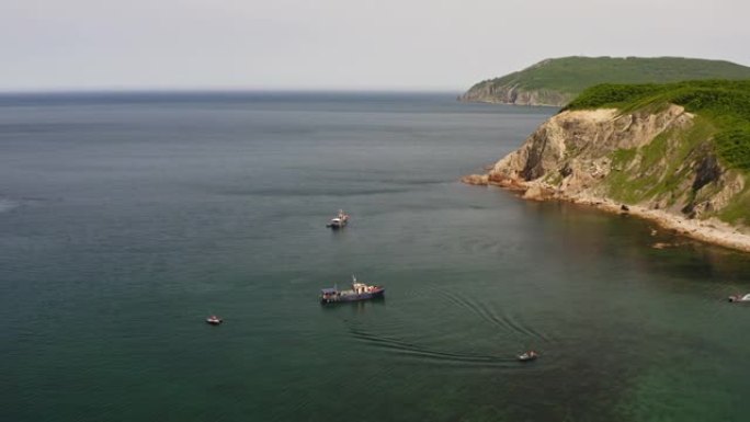 在美丽的岩石海角附近停泊的钓鱼纵帆船的无人机视图