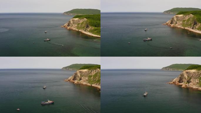 在美丽的岩石海角附近停泊的钓鱼纵帆船的无人机视图