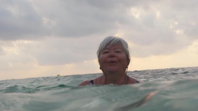 头发花白的老年妇女，早上在海上游泳