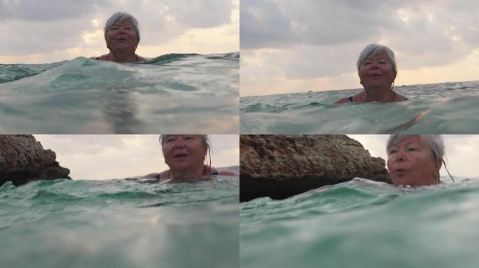 头发花白的老年妇女，早上在海上游泳
