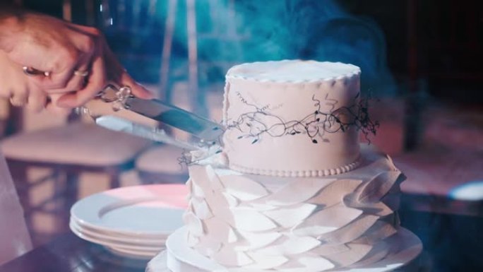 新婚夫妇的手用刀切开婚礼蛋糕