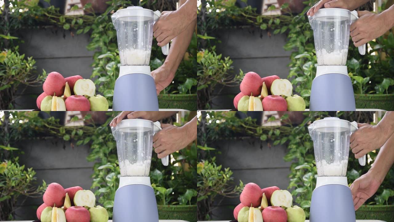 用电动搅拌器制作新鲜的苹果和番石榴汁。
