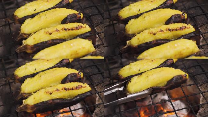在传统的炭炉上向下倾斜烤去皮的香蕉。有人捡起来。烧烤食物。泰国菜。热带地区的甜果甜点。