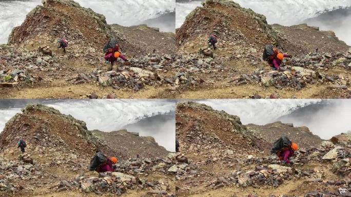 一个背着大背包的疲倦游客沿着山间小路跌跌撞撞地走过石头和巨石