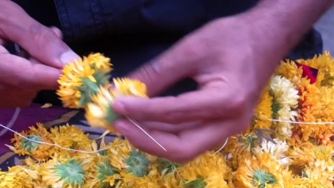 一个人制作花环和装饰辫子结或花，叶子或其他材料的花环的稳定镜头。