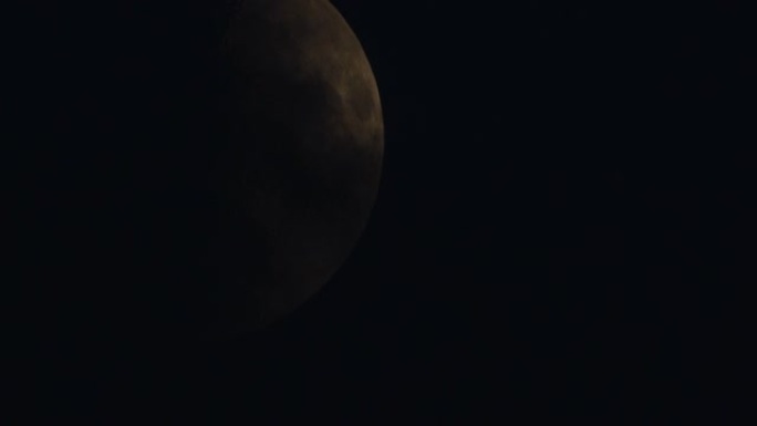 特写夜晚欧洲金色半月相，黑色背景上有弹坑表面纹理细节，空间空白，用作桌面。温暖的彩色月亮是由低空的天