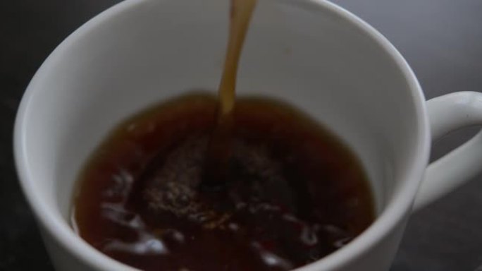 慢动作将黑咖啡倒入杯中。新鲜的早晨倒在红茶上特写。选择性聚焦。从咖啡机特写镜头中倒入杯中的咖啡的慢动