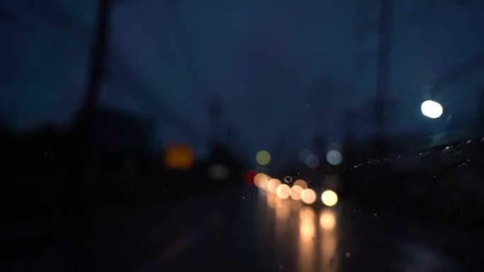 Clos在道路或街道上e up.ca r。在下雨的夜晚开车。交通中聚焦模糊的光线，小雨水击中前后视镜