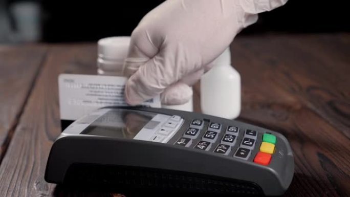 一个戴着手套的女人用卡在药房支付药品的特写镜头。