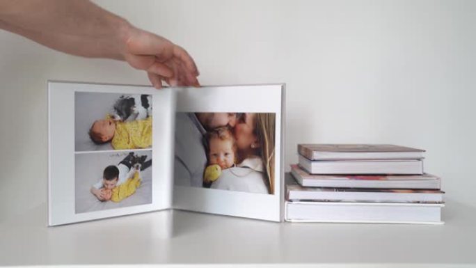 在白色桌叶上，通过写真本拍摄的新生儿家庭照片。