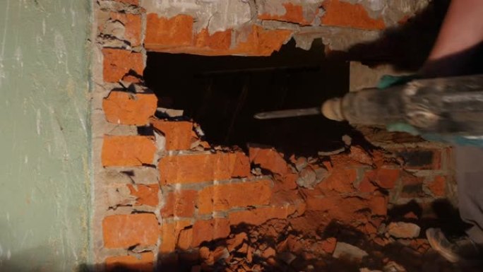一名工人用手提钻在砖墙上打一个洞