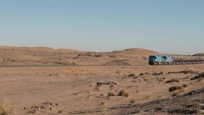 沙质沙漠中的铁轨上的货物列车