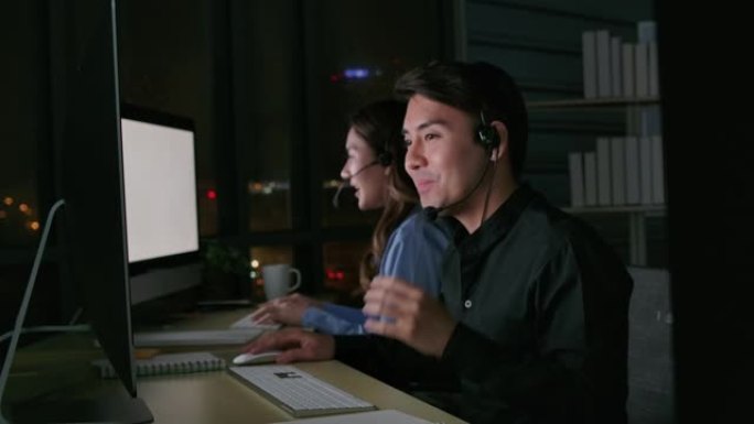 热线接线员。呼叫中心员工晚上在现代办公室使用电脑和耳机