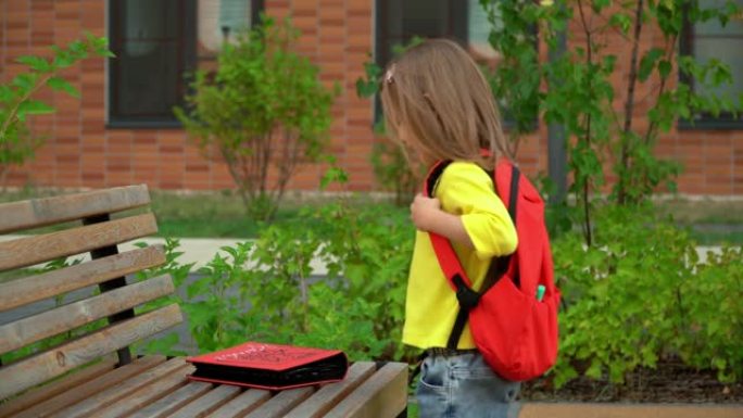 学校休息。笑的女孩在校园里奔跑并脱下背包。教育