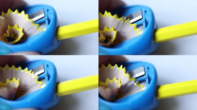 黄色木铅笔刨花从蓝色卷笔刀中出来特写视图