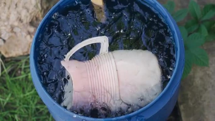 雨后，一个塑料壶漂浮在花园里的一桶水中。从上方射击