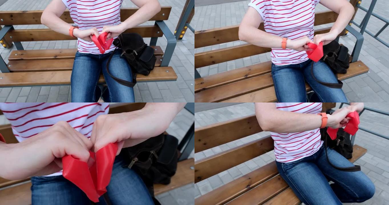 女人坐在长凳上，用阻力带运动，她总是把它放在包里