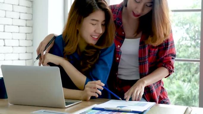 亚洲同事在工作中的友谊带着笑脸。幸福两位女同事在办公桌上一起工作团队会议。与电脑笔记本电脑创业公司合