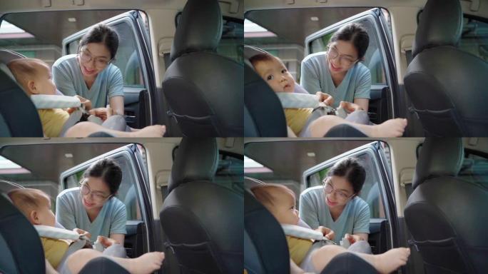 妈妈解开婴儿汽车座椅的安全带