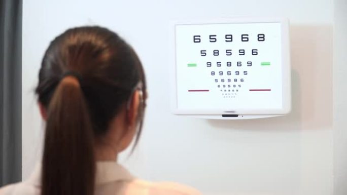 验光师办公室，亚洲年轻女子穿着可调节的瞳孔间距离试验框架，用于测试视力测试阅读视力表，Snellen