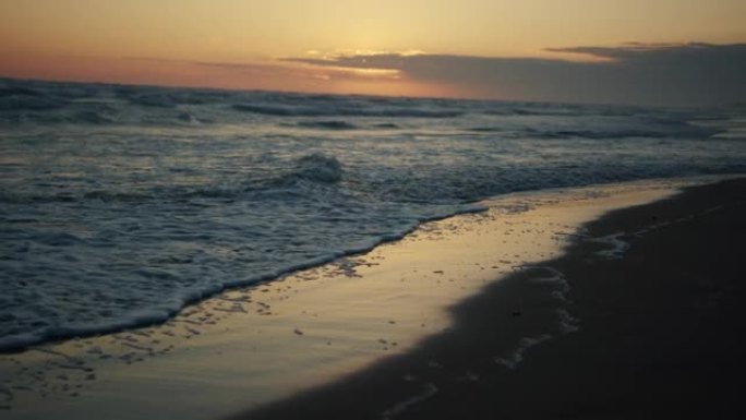 全高清特写镜头，海浪在海滩的金色沙滩上留下脚印