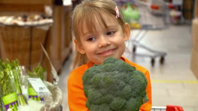 购物车中的小女孩在超市的蔬菜部门选择西兰花。商店购物产品的概念。健康素食