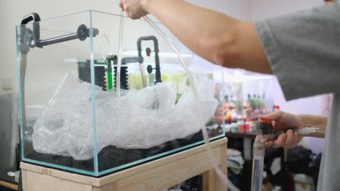 在家中设置水族箱的步骤，方法是使用气泡包装和虹吸管将水注入新鲜水箱
