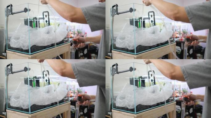 在家中设置水族箱的步骤，方法是使用气泡包装和虹吸管将水注入新鲜水箱