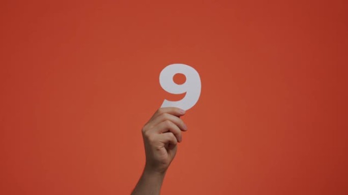 九号在手。手臂显示数字，第九个数字由雕刻纸制成，用于投票或学习