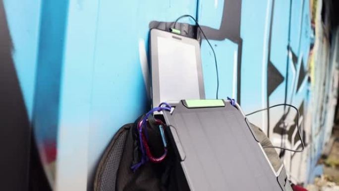 可再生能源的概念。平板电脑由背包上的便携式太阳能电池板电池充电。