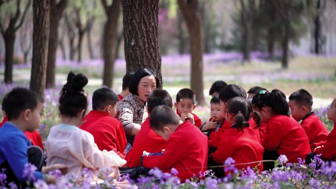 幼儿教师在花丛中给孩子们讲故事