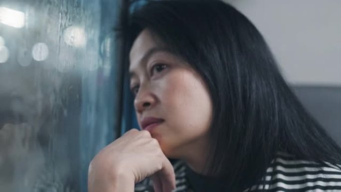 亚洲妇女独自乘火车旅行，透过窗户看风景