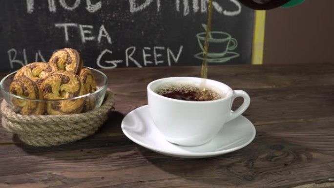 咖啡馆桌上的一杯茶和自制饼干。茶从透明的茶壶中倒出。menu.4 k