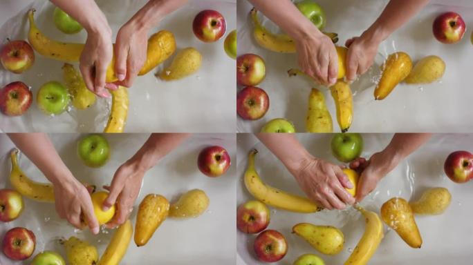 女性手洗香蕉梨苹果柠檬。手洗新鲜蔬菜水果用水在盆中慢动作。素食家庭厨房。新鲜收获。清洗水果和蔬菜特写