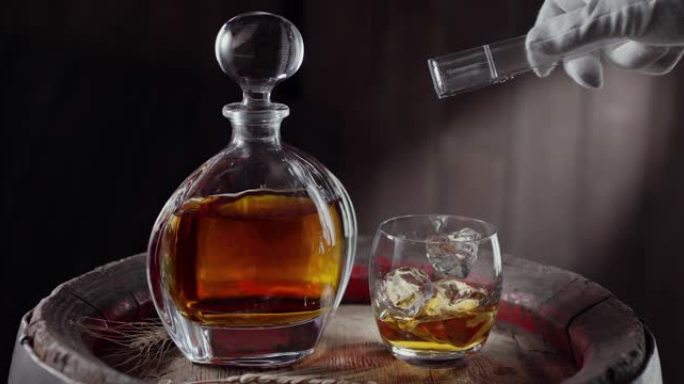 一块冰块慢慢落入玻璃杯中，站在一桶老式威士忌上，从瓶子里出来的威士忌立即倒入玻璃杯中。附近有一个装有