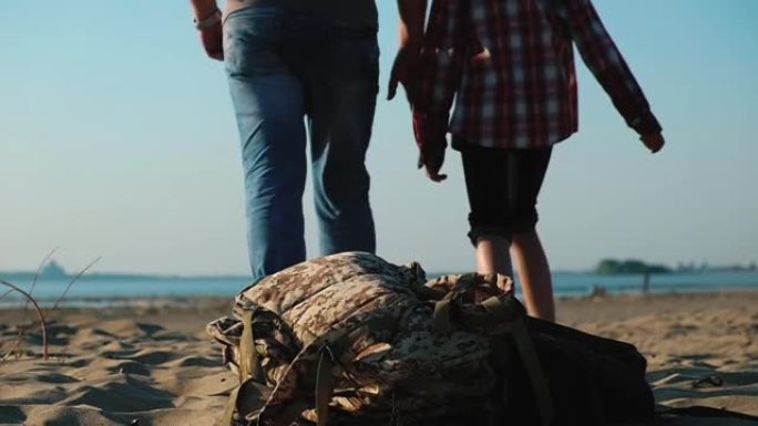 幸福的家庭把背包扔在沙滩上，沿着沙滩走向大海。