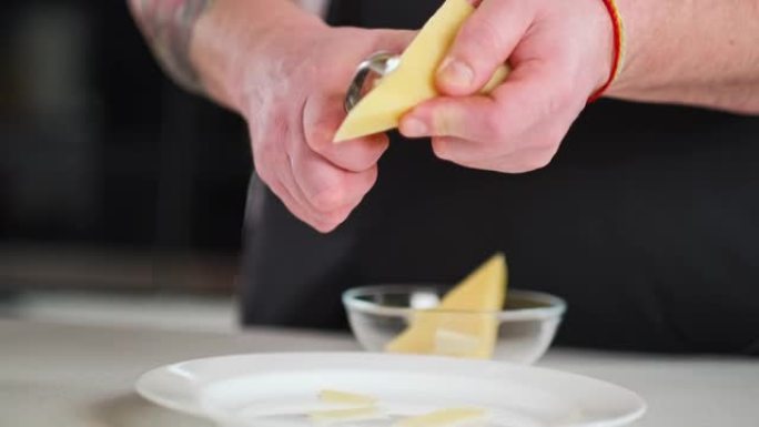 男主厨用特制的奶酪刀将坚硬的帕尔马干酪切开并摩擦。餐厅的专业厨房。