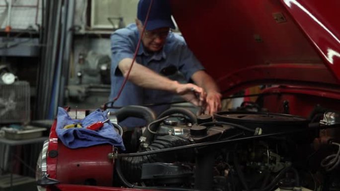 在1983车辆的引擎盖下工作的机械师。