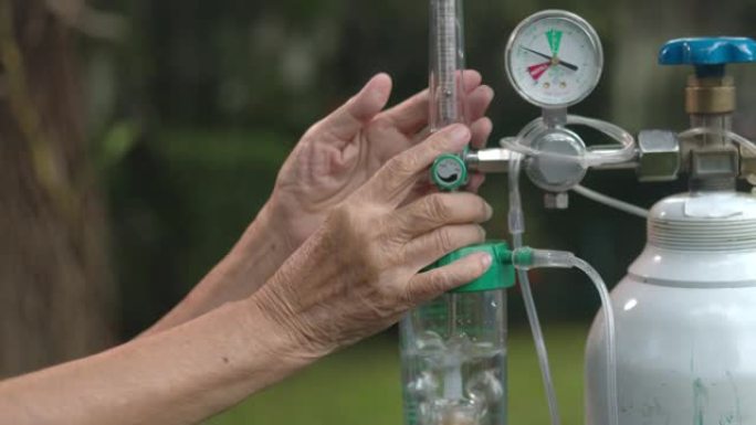 老年妇女拿着带氧气瓶的流量调节器