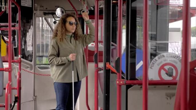 公共汽车上的年轻盲人女子用拐杖抓住把手
