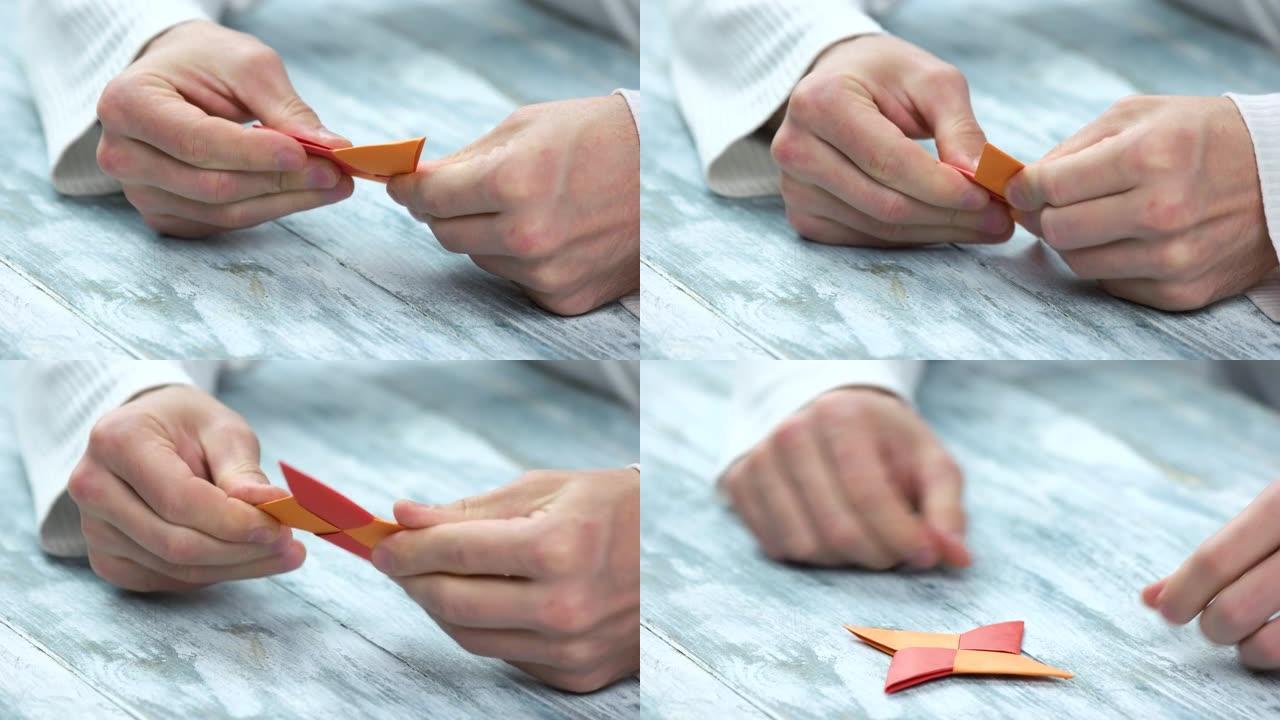 手做四个尖的手里剑折纸。